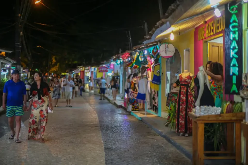 Passeio noturno em Arraial d’Ajuda com guia local: ruas iluminadas, bares animados e vista do Rio Buranhém.
