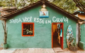 Casa em Caraíva com a frase "Sorria você está em Caraíva" e prancha de surf. Um dos charmes do que fazer em Caraíva.