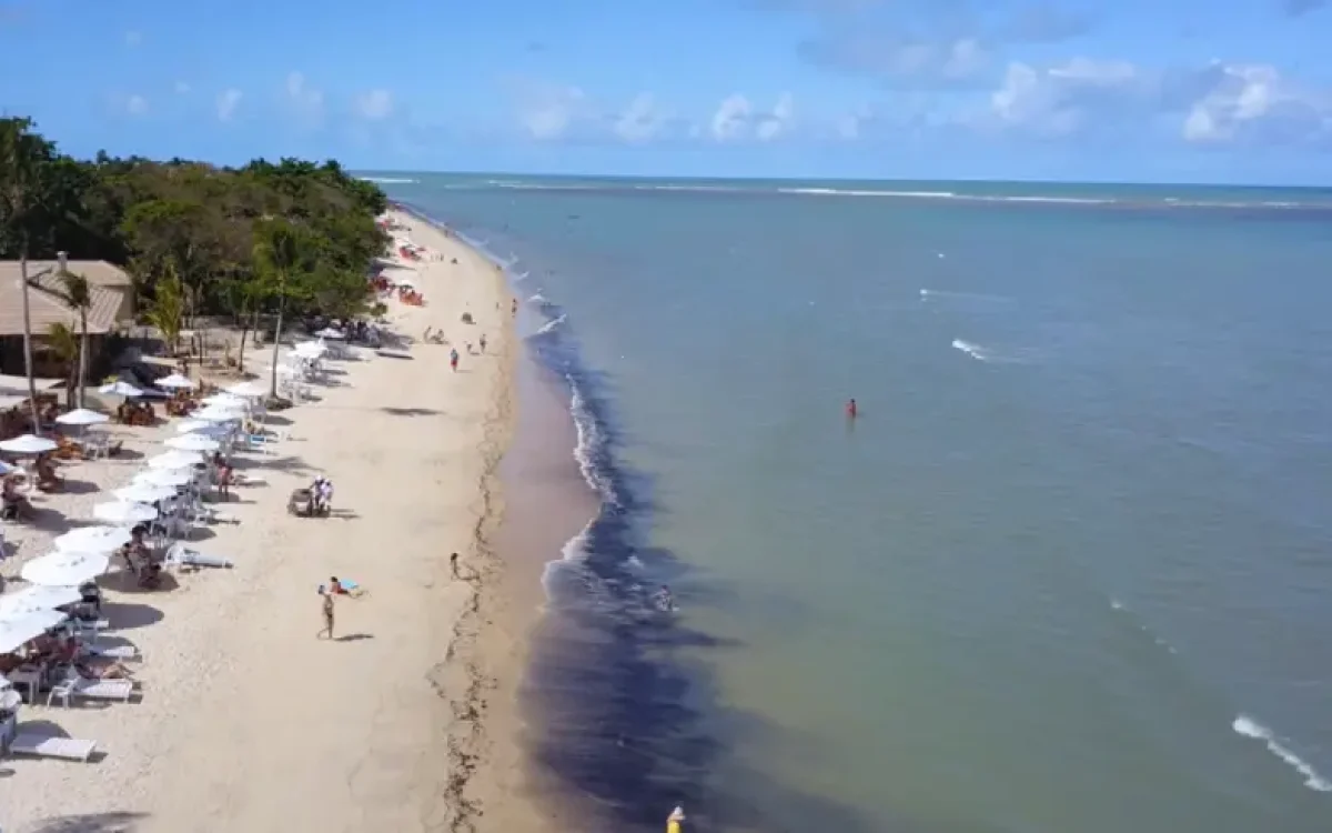 Um ângulo aéreo que revela a serenidade da Praia do Mutá, com suas águas convidativas e a infraestrutura acolhedora para um dia de sol.
