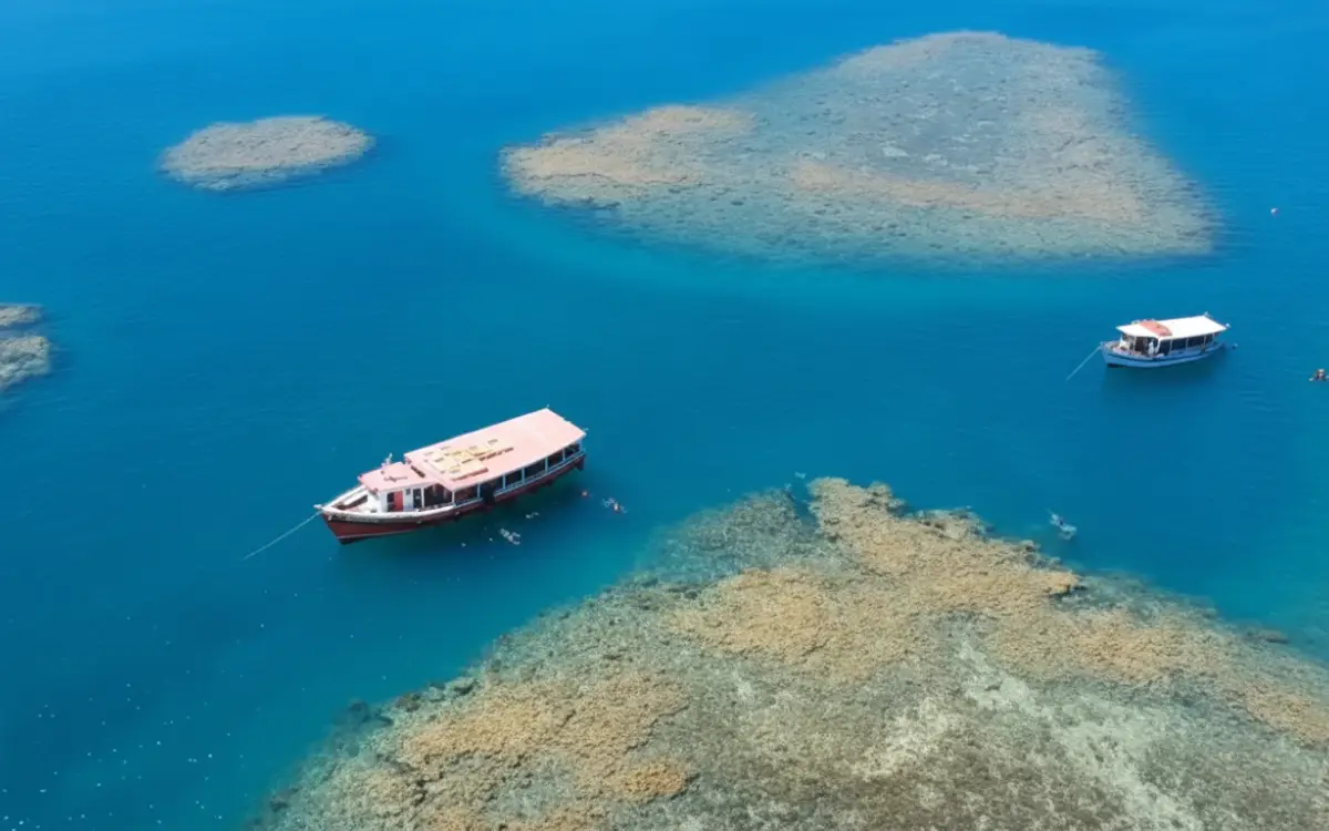 Escunas ancoradas nas piscinas naturais do Parque Marinho de Recife de Fora em Porto Seguro, com corais visíveis em águas azul-turquesa.