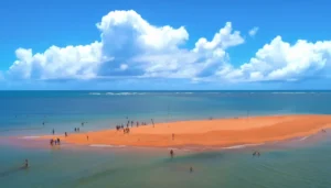 Vista aérea do passeio de escuna Coroa Alta em Santa Cruz Cabrália, mostrando o banco de areia, piscinas naturais e visitantes mergulhando em águas cristalinas.