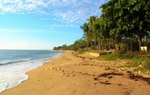 Praia de Araçaípe em Arraial d'Ajuda, Bahia, com areia dourada, coqueiros e piscinas naturais na maré baixa, perfeita para famílias.