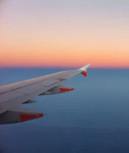 Asa de avião sobre o mar ao pôr do sol, ilustrando voos em oferta para Porto Seguro.