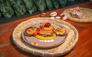 Prato gourmet com camarões grelhados e arroz cremoso, servido em travessa de palha, representando a culinária do Festival Gastronômico Esquina do Mundo em Arraial d'Ajuda.