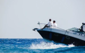 Passeio de lancha em Trancoso com duas pessoas sentadas na proa, navegando em mar azul e criando espuma.