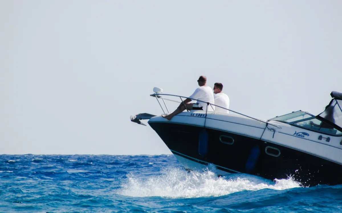 Passeio de lancha em Trancoso com duas pessoas sentadas na proa, navegando em mar azul e criando espuma.