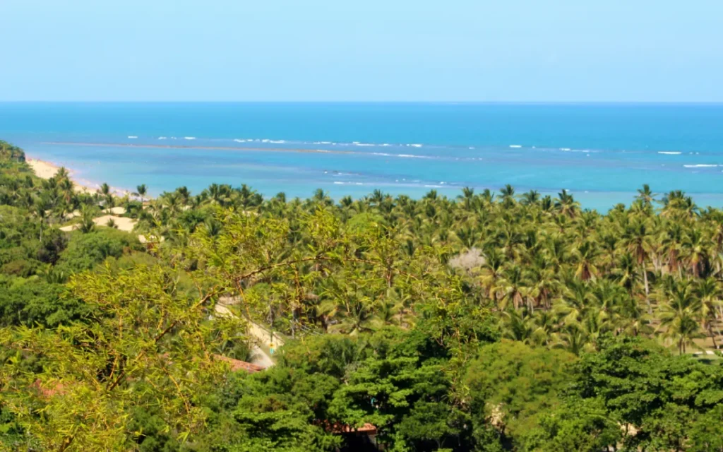 Passeio Trancoso Arraial d'Ajuda saindo de Porto Seguro: vista aérea do Quadrado de Trancoso com igreja e coqueiros ao entardecer.