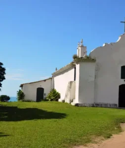 Igreja de São João Batista no Quadrado de Trancoso com gramado e vista para o mar azul.