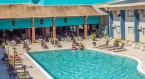 Hóspedes aproveitando a piscina do Nauticomar Resort em Porto Seguro, com vista para a área de mesas, espreguiçadeiras e arquitetura moderna do hotel.