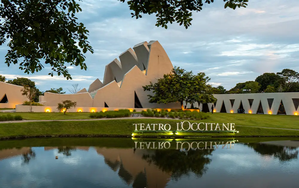 Orquestra se apresentando no palco do Teatro L’Occitane durante o Festival Música em Trancoso, com arquitetura aberta e iluminação cênica.