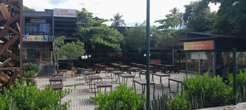 Vista externa do Quintal Centro Gastronômico na Orla Norte de Porto Seguro, mostrando mesas e cadeiras em uma área ao ar livre, ideal para quem procura onde comer na região.