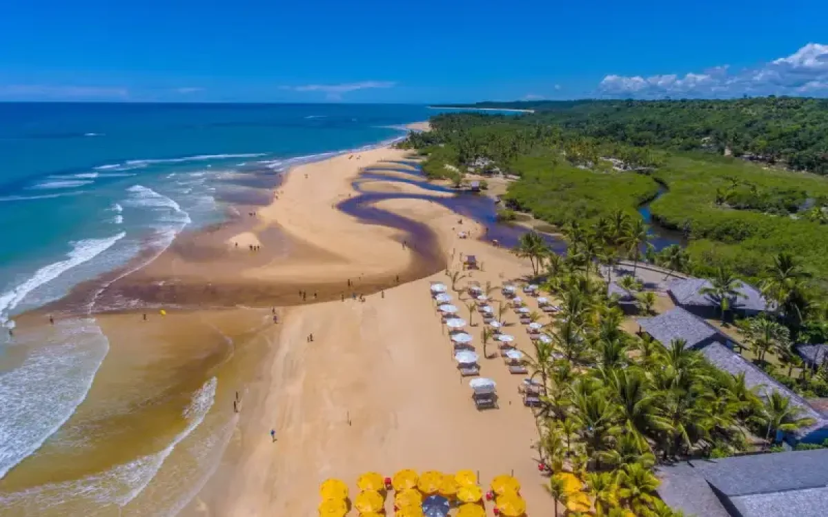 Trancoso: passeio encantador saindo de Porto Seguro. Vista aérea do mar azul-turquesa, foz do rio e coqueirais.